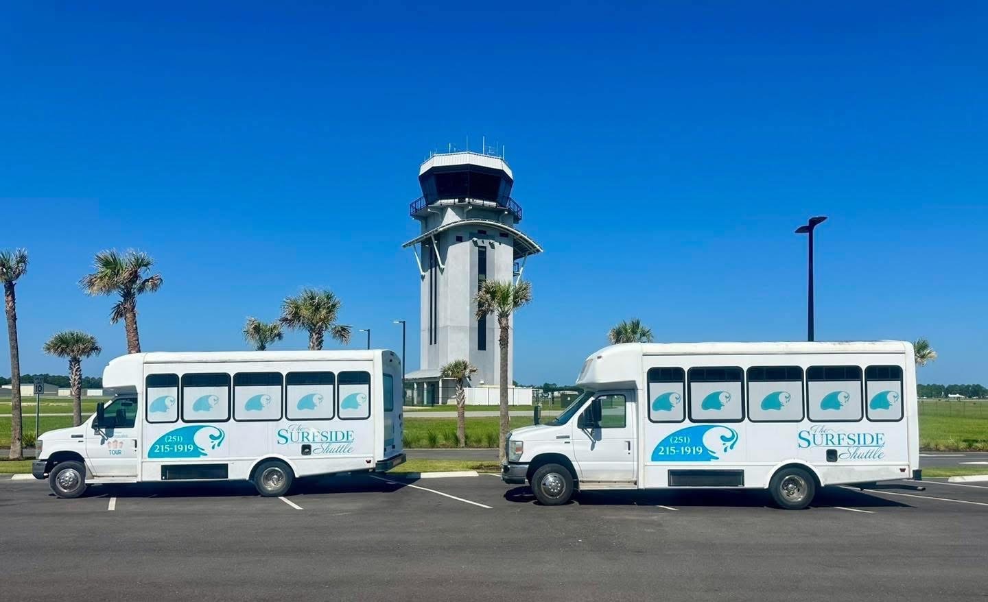 Shuttles Parked in Front of an Airport Control Tower Under a Clear Blue Sky, Showcasing Transportation Options for Travelers.