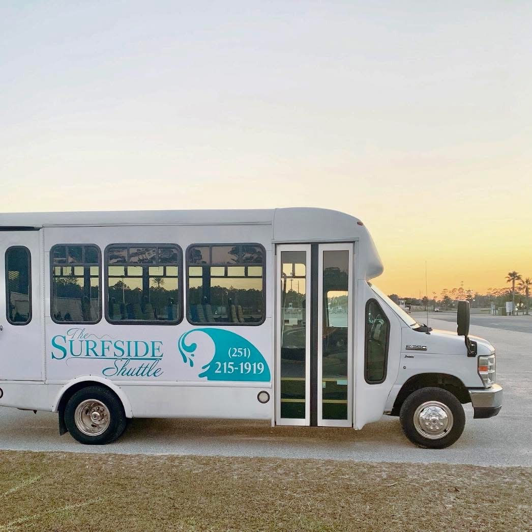Sureside Shuttle Bus Parked Under a Sunset, Highlighting Its Branding and Contact Number for Local Transportation Services.